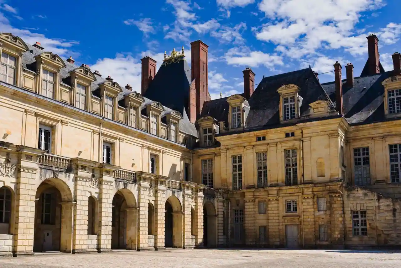 Façade en pierre dorée et cour intérieure à arcades du château de Fontainebleau