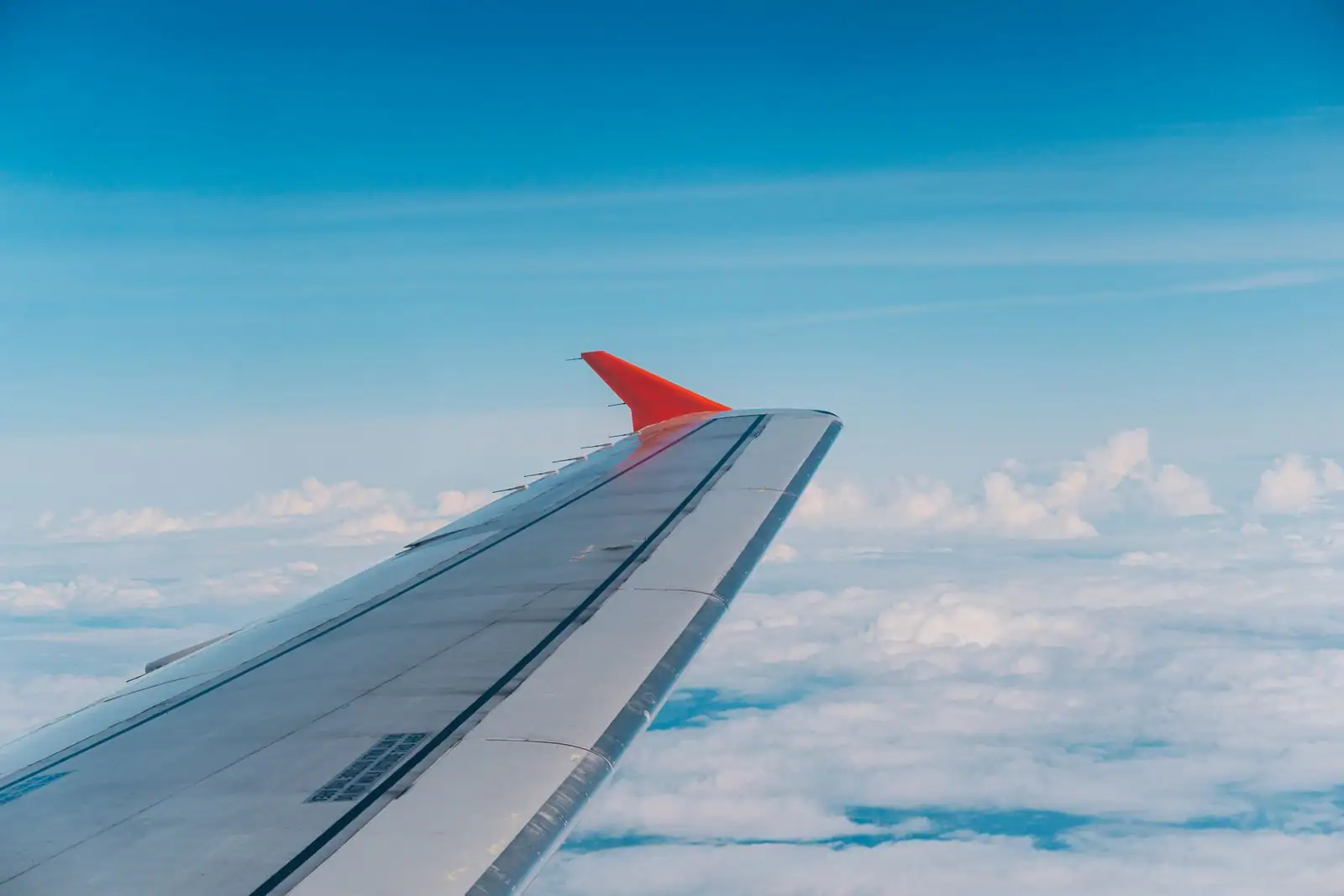 Aile d'un avion de ligne en vol au-dessus d'une couche de nuages, vue depuis le hublot