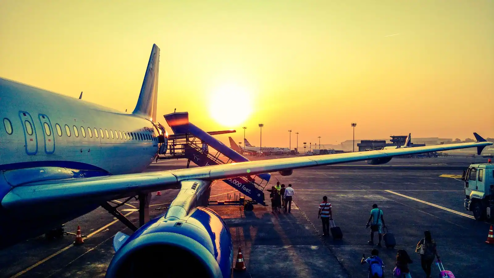 Passagers embarquant dans un avion de ligne sur le tarmac au coucher du soleil