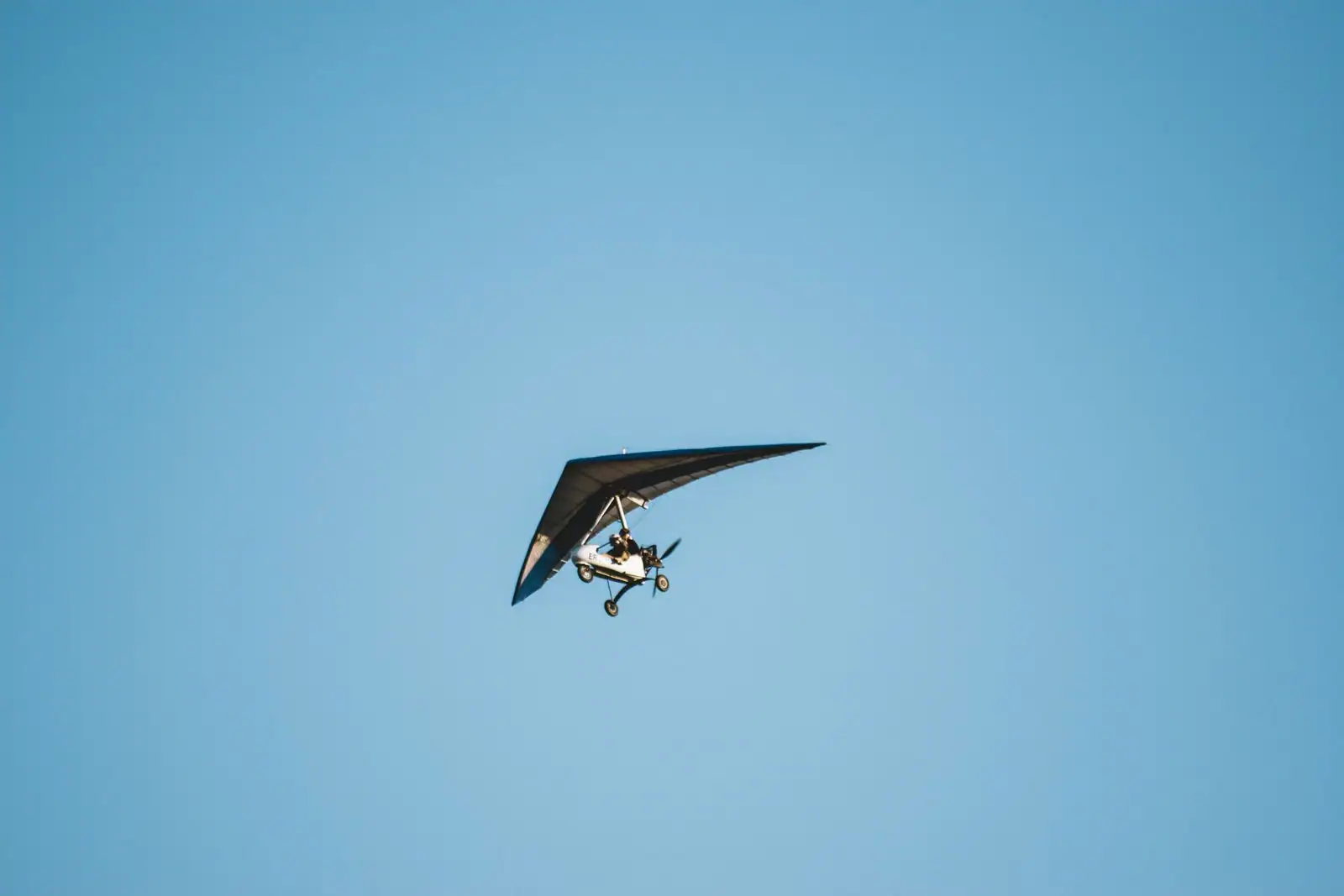 ULM pendulaire, aile delta et chariot motorisé, en vol dans un ciel bleu dégagé