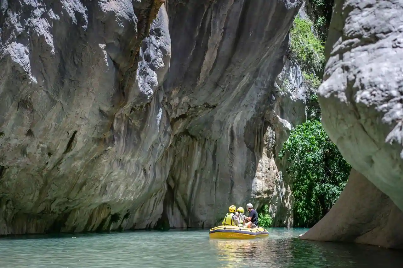 Embarcation de rafting sur une rivière verte au fond des gorges, entre de hautes falaises calcaires