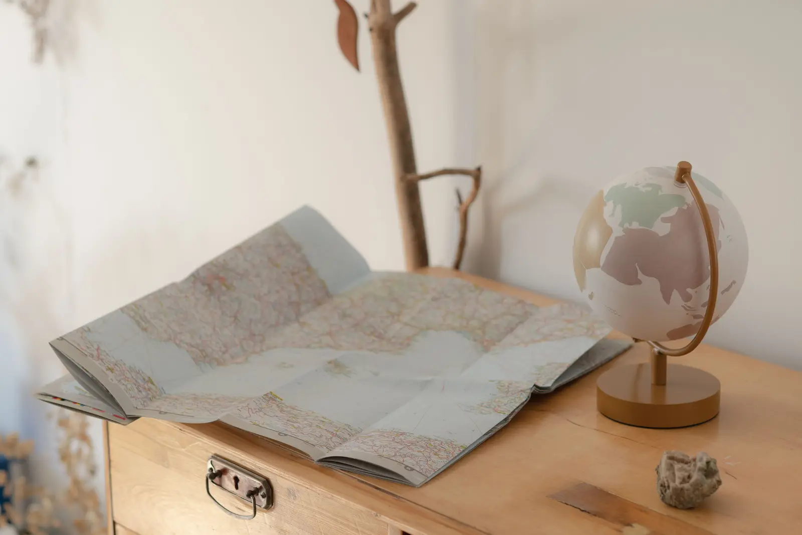 Petit globe terrestre et carte du monde dépliée posés sur une commode en bois clair