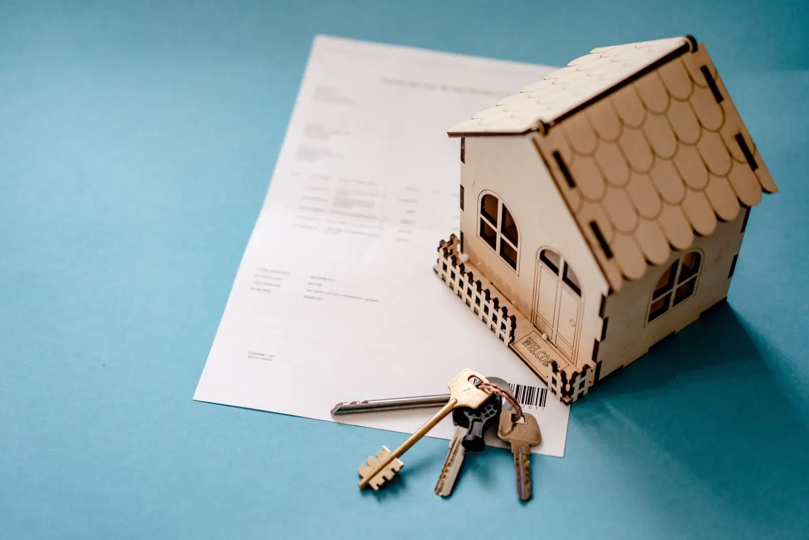 Maquette de maison en bois posée sur un contrat avec un trousseau de clés, évoquant un crédit immobilier.