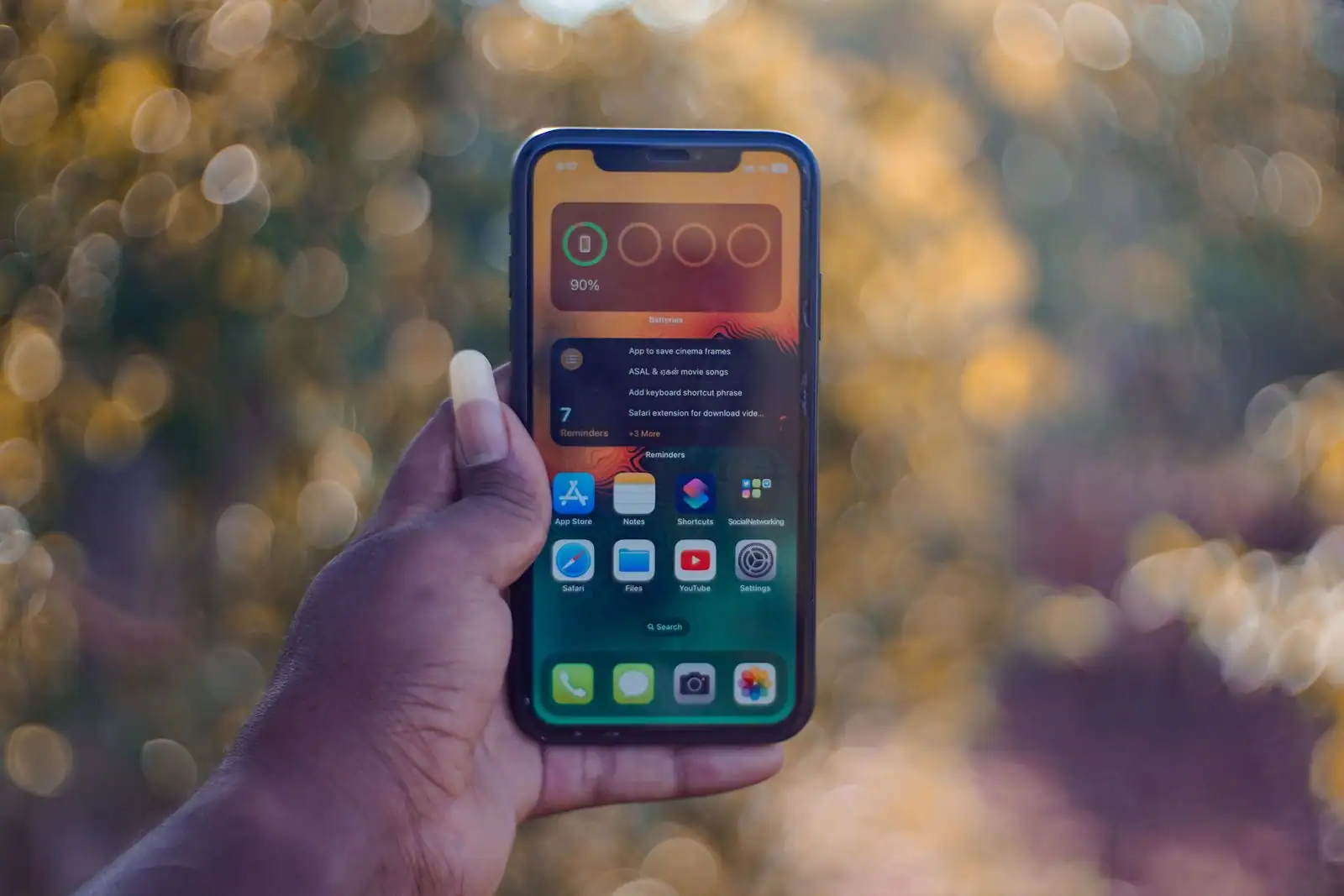 Main tenant un smartphone affichant des applications, illustrant le choix d'un forfait mobile.