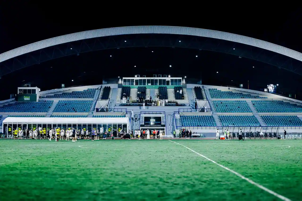 Stade de football moderne illuminé la nuit, pelouse verte au premier plan