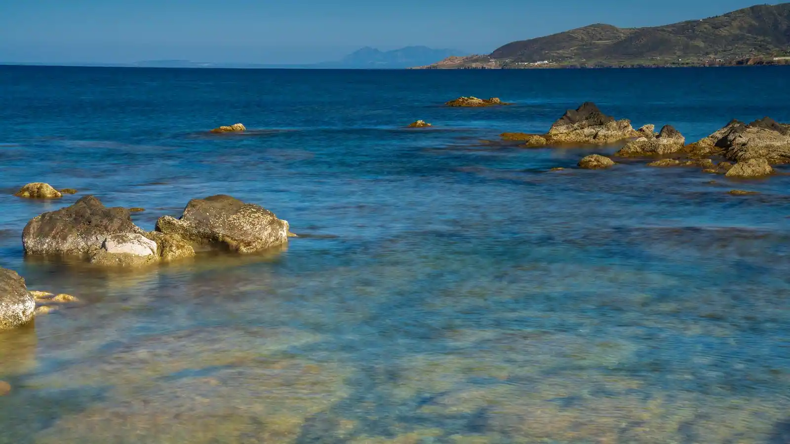 Littoral méditerranéen aux eaux claires et turquoise, rochers affleurant près du rivage.