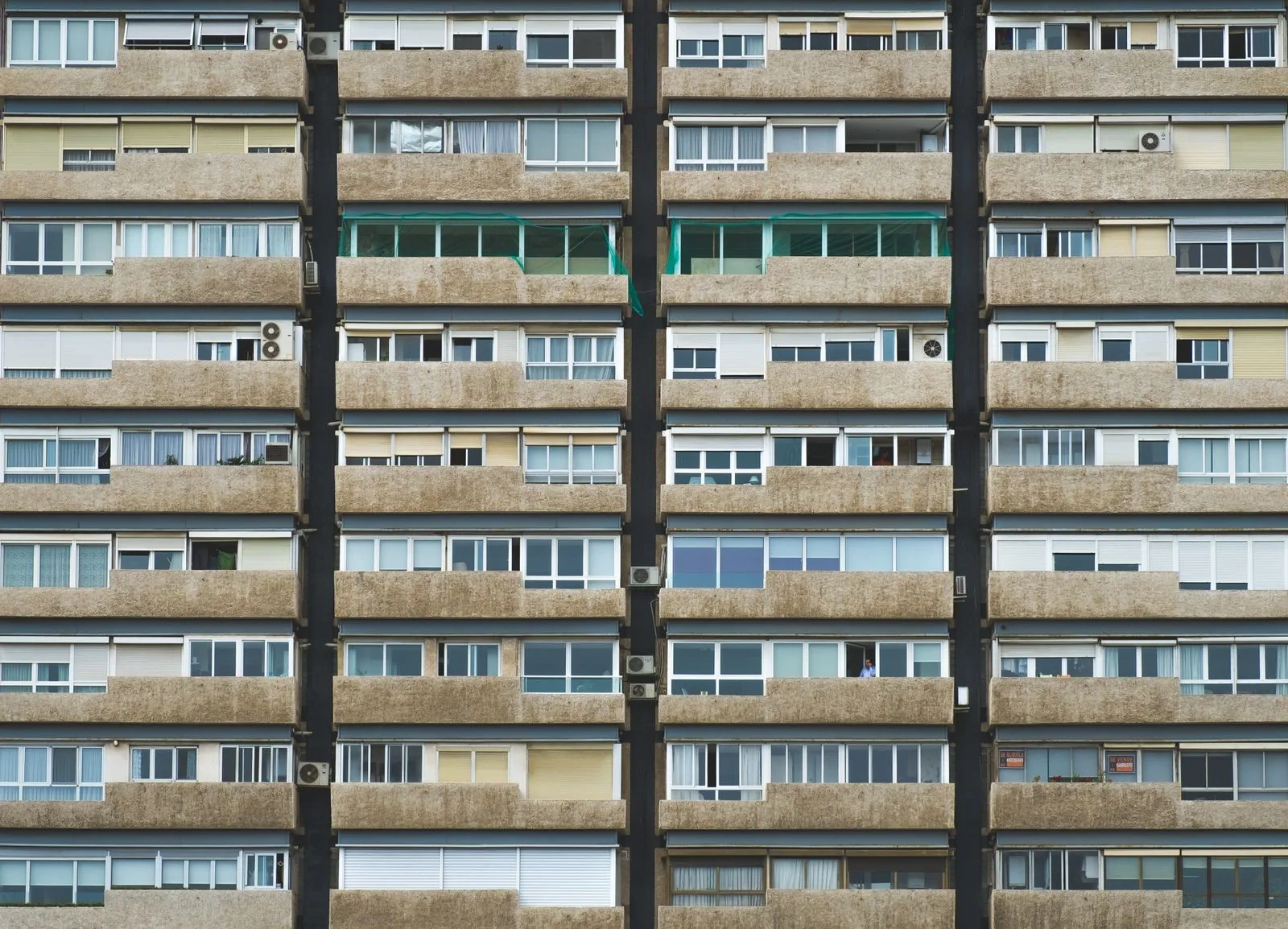 Grand immeuble d'habitation collectif aux nombreuses fenêtres et balcons, façade en béton.