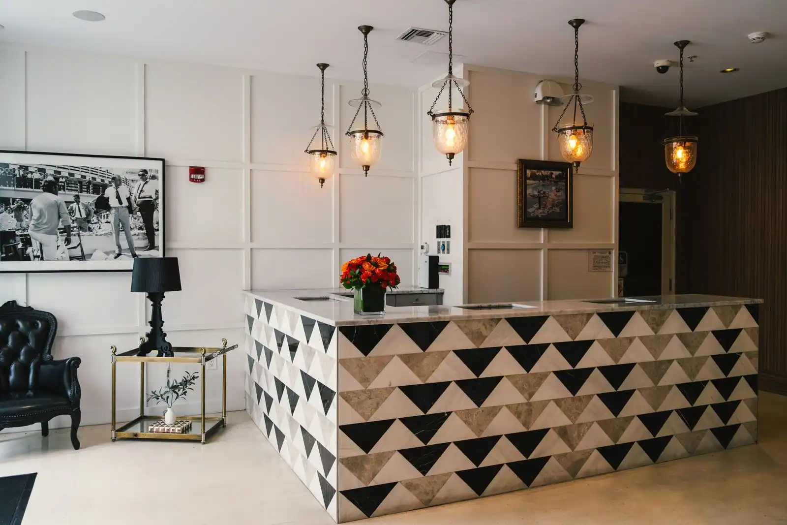 Réception d'un boutique-hôtel à la décoration éclectique, suspensions vintage, fauteuil en cuir et œuvres encadrées.