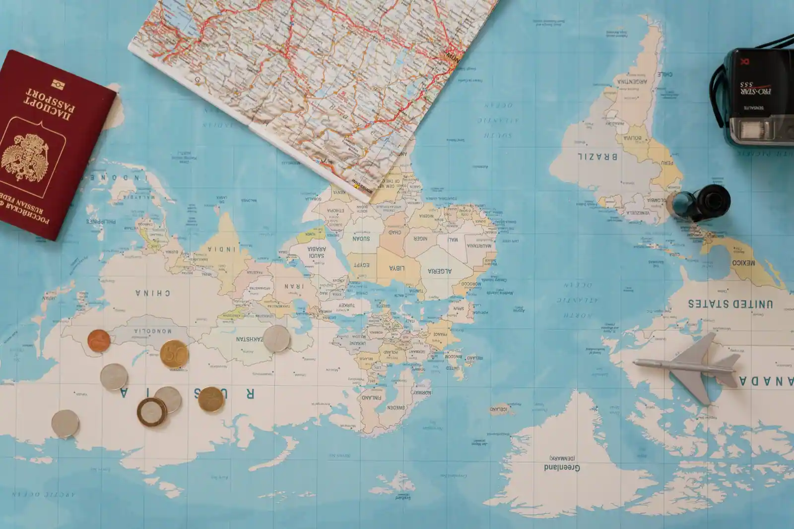 Passeport, carte du monde, pièces de monnaie et appareil photo réunis pour préparer un voyage.