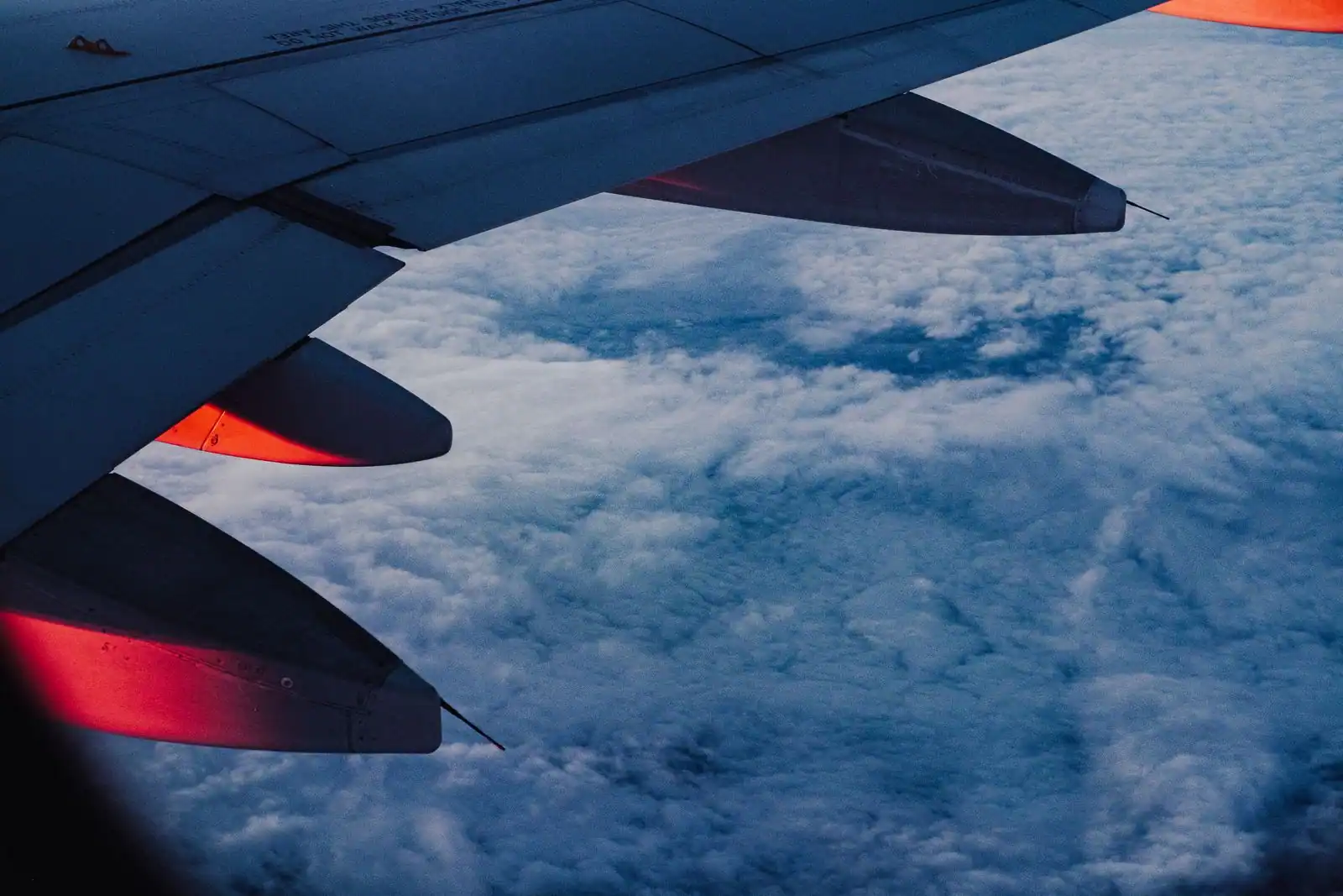 Aile d'un avion de ligne vue depuis le hublot, au-dessus d'une couche de nuages
