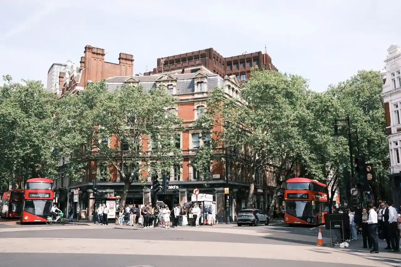 Rue animée de Londres avec deux bus rouges à impériale et des bâtiments victoriens