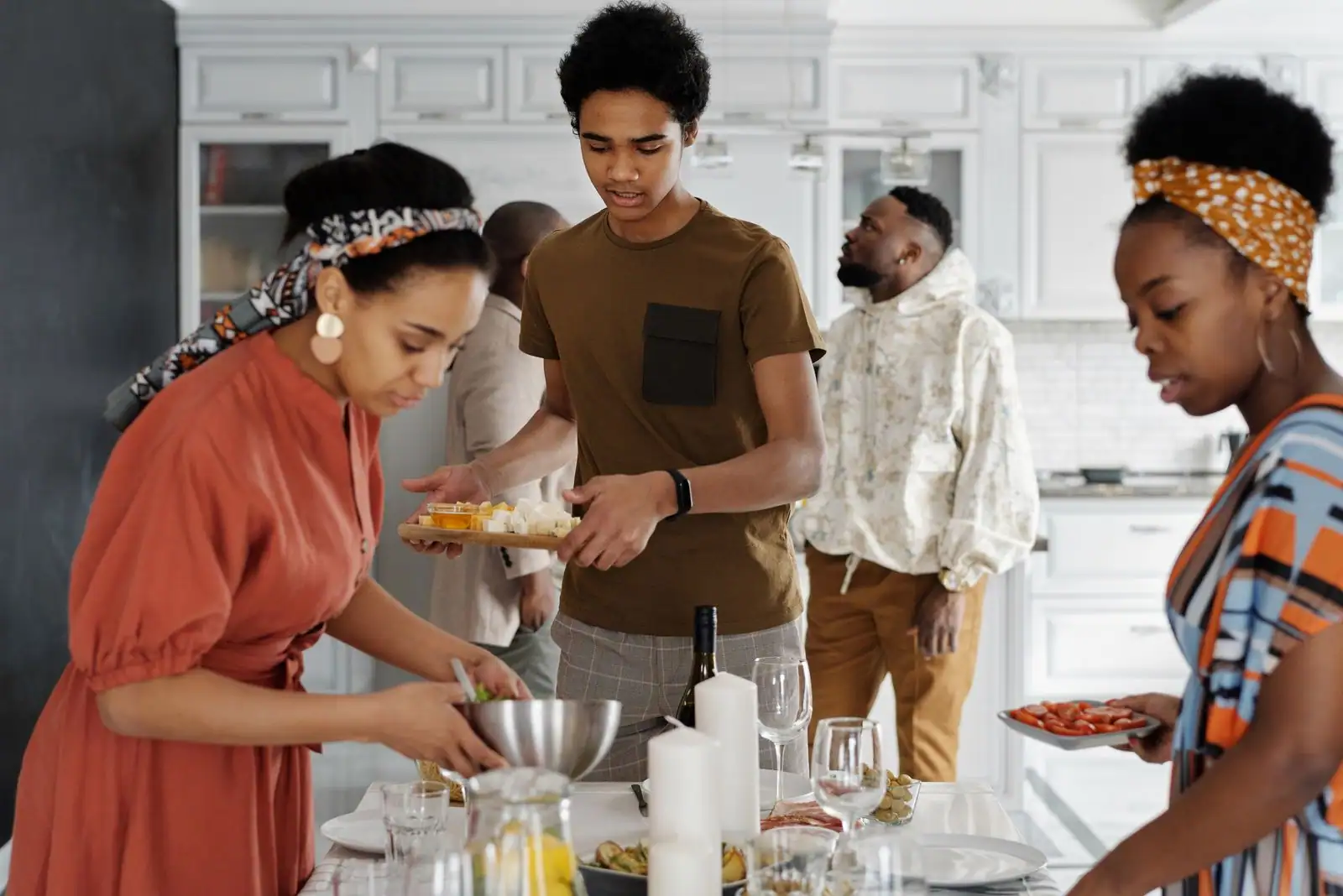 Adolescent aidant à préparer la table du repas en famille dans une cuisine lumineuse