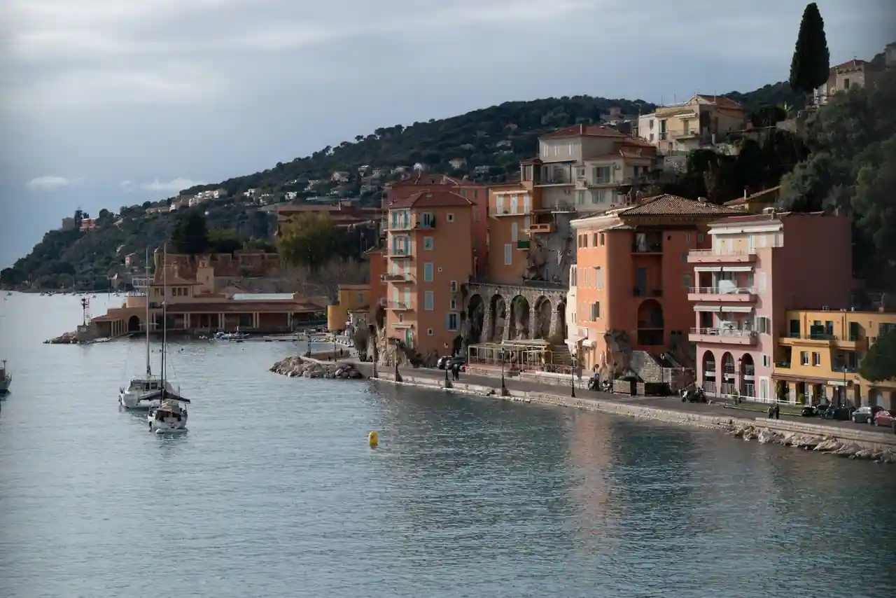 Village coloré en bord de mer méditerranéen sur la Côte d'Azur, avec un voilier au mouillage