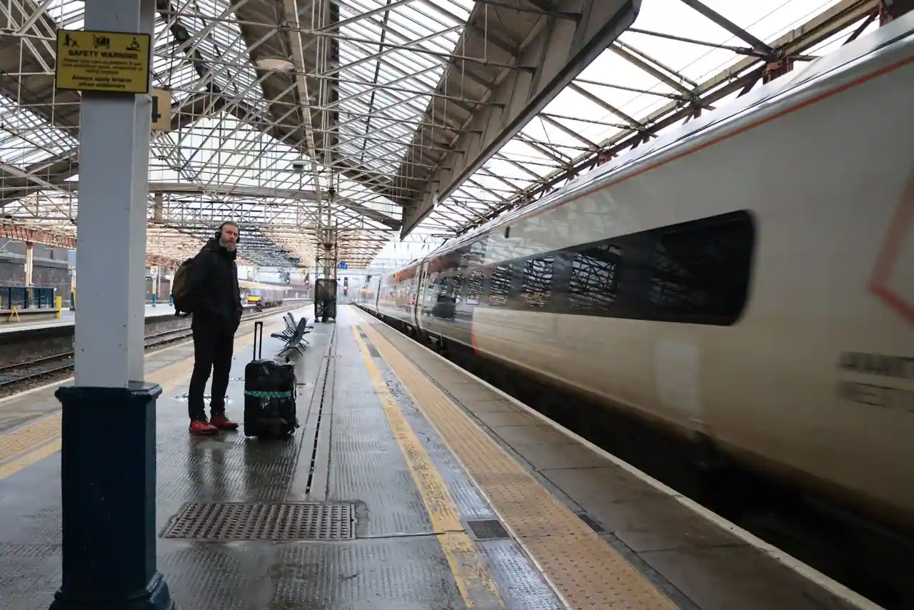 Voyageur avec une valise attendant un train à quai dans une gare britannique
