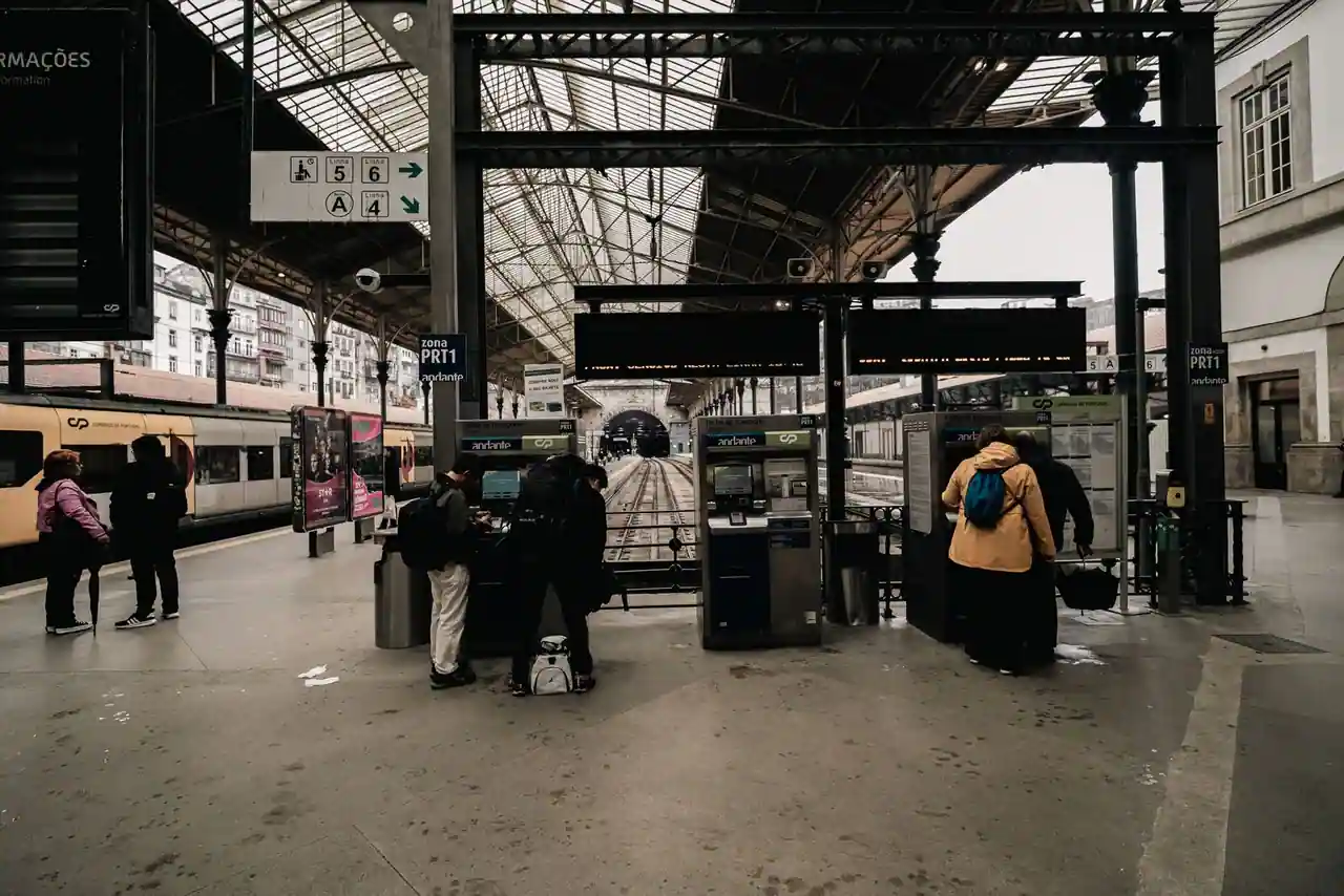 Hall animé d'une gare avec quais et voyageurs devant les distributeurs de billets de train.