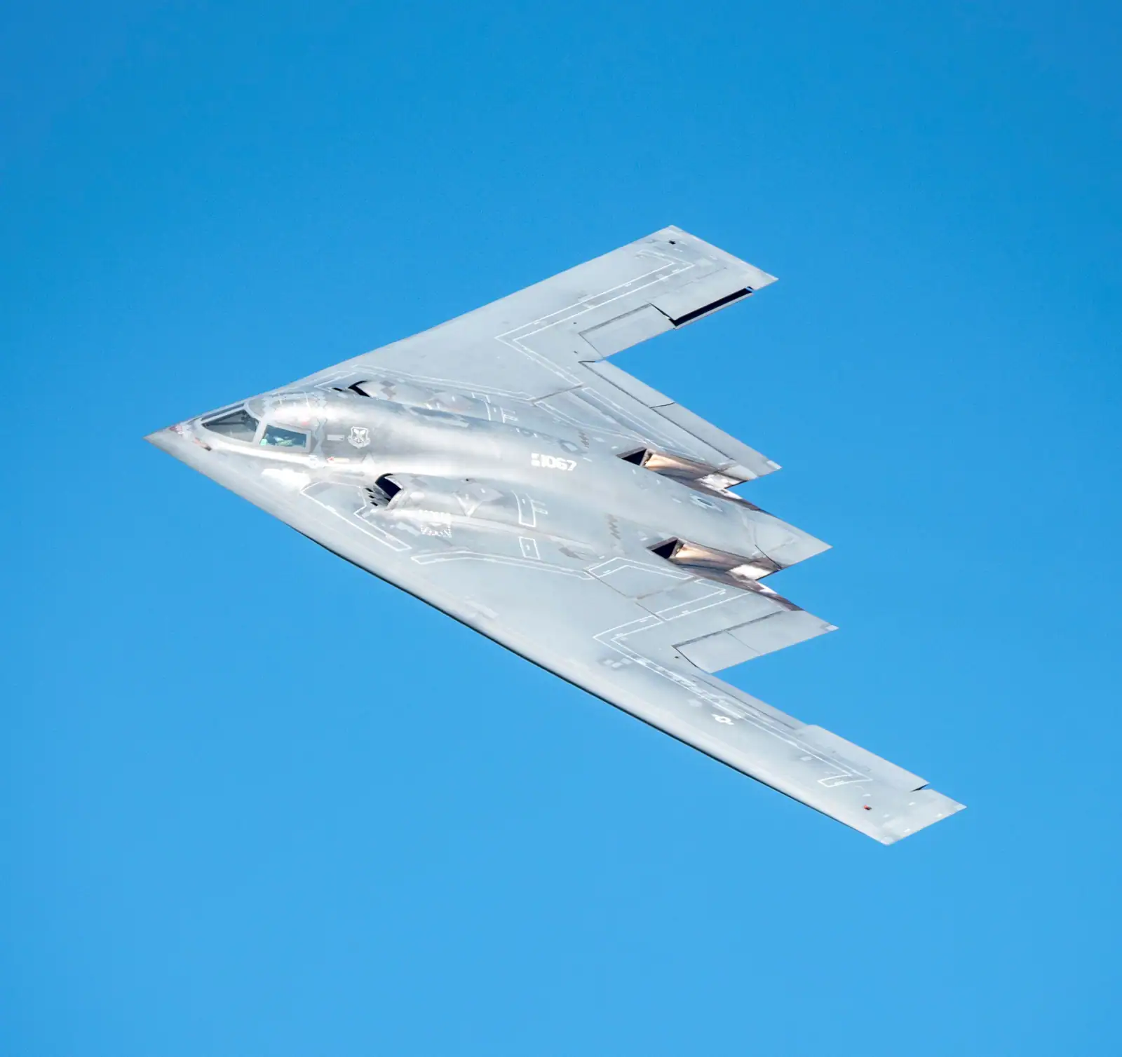 Un B-2 Spirit vu de dessus en virage : aile volante sans dérive, au bord de fuite dentelé.