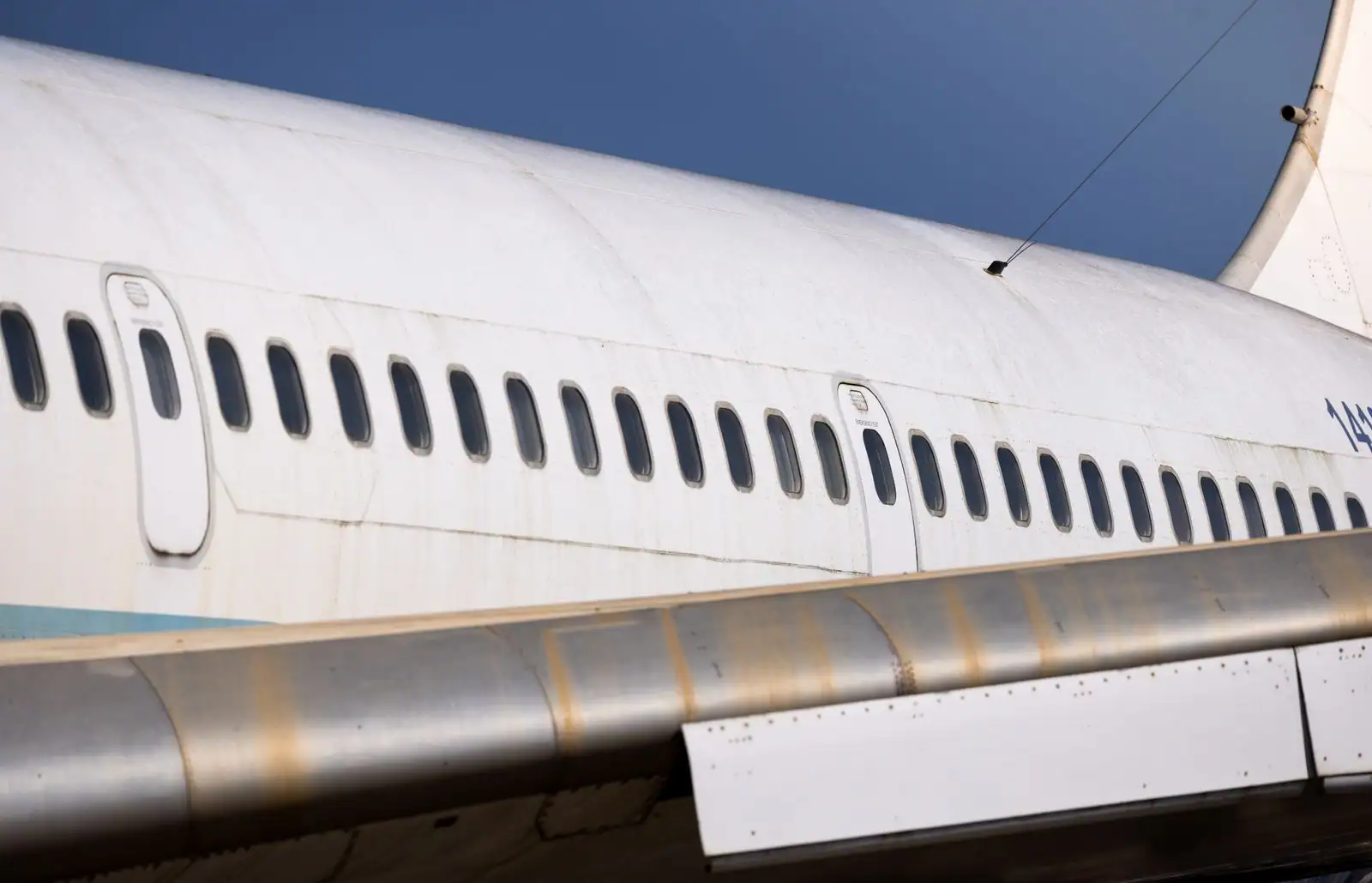 Fuselage d'un avion de ligne à réaction ancien, longue rangée de hublots de cabine sous un ciel bleu
