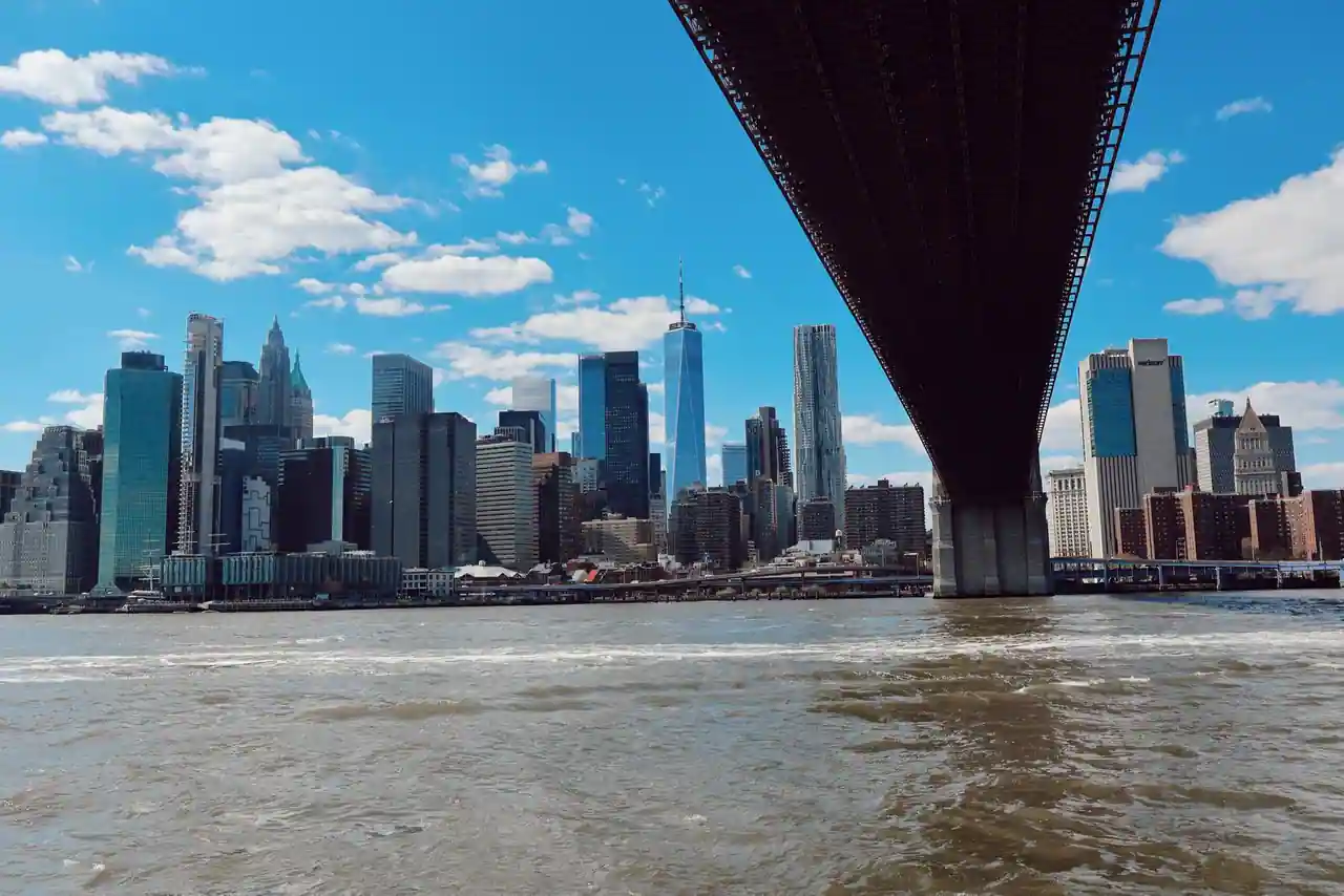 Gratte-ciel de Lower Manhattan vus depuis l'East River sous le tablier d'un pont suspendu