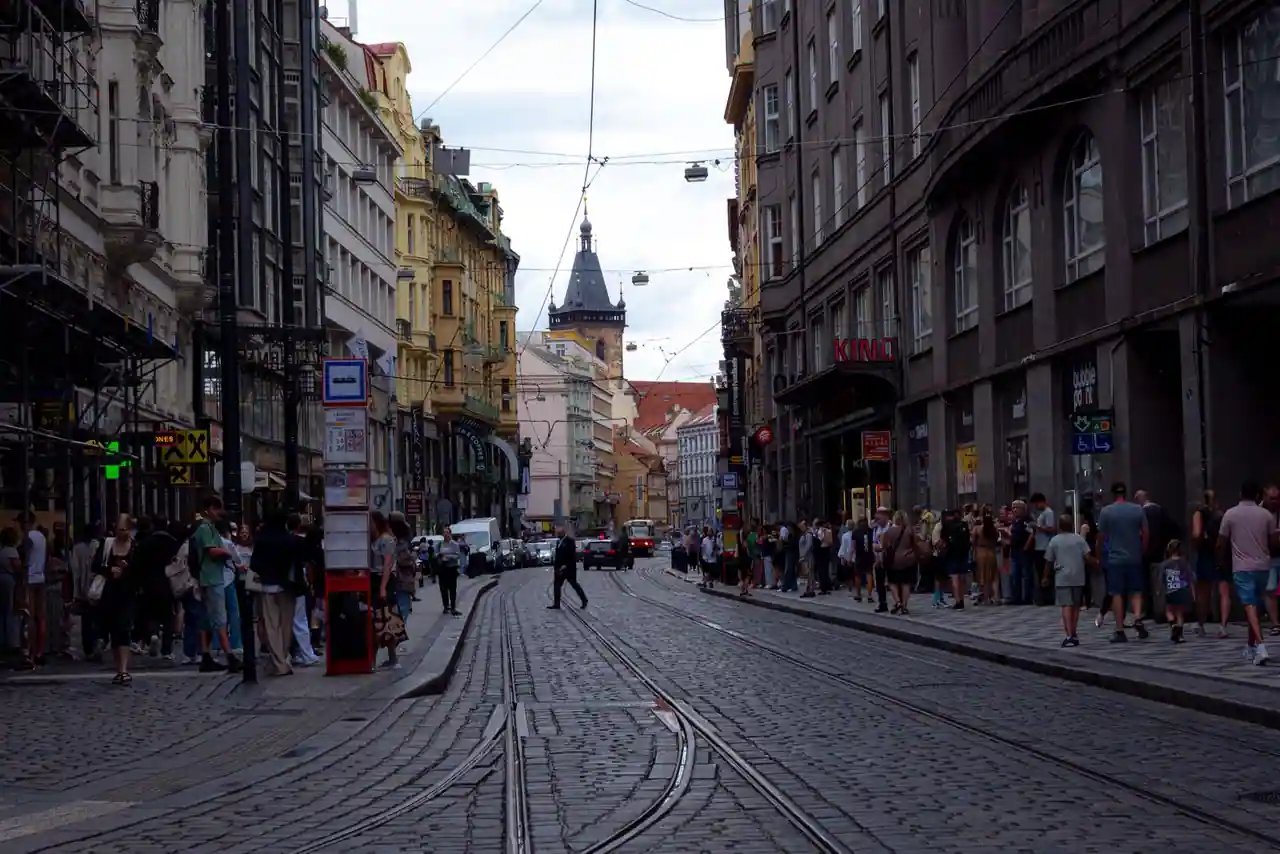 Rue pavée d'un centre historique européen avec rails de tramway, façades anciennes et nombreux passants