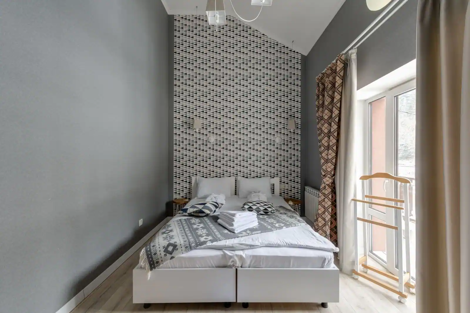 Chambre d'hôtel étroite au mobilier réduit : deux lits accolés, serviettes pliées et porte-bagages.