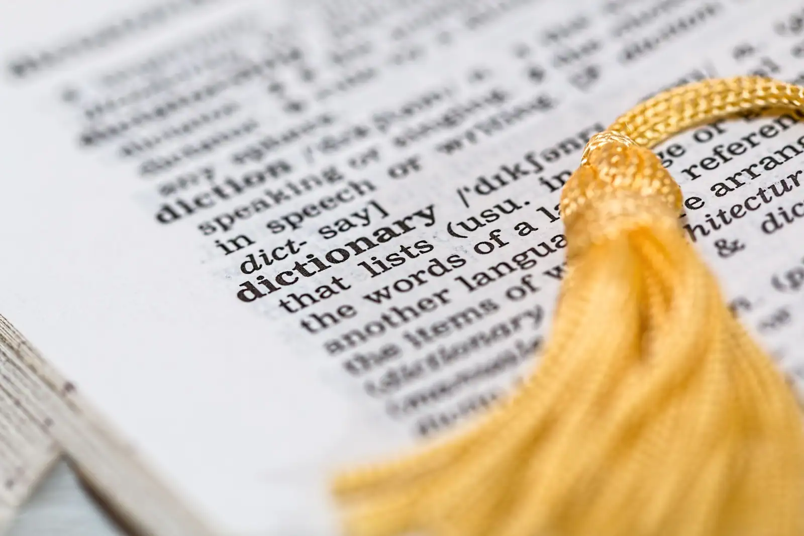 Page de dictionnaire anglais en gros plan sur l'entrée « dictionary », avec un signet doré