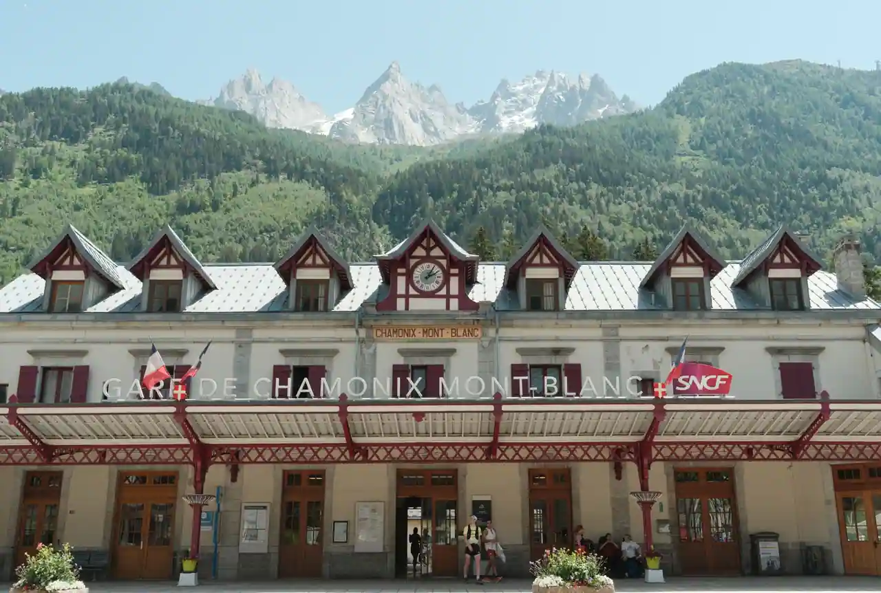 Façade de la gare SNCF de Chamonix-Mont-Blanc, avec les aiguilles rocheuses des Alpes derrière.