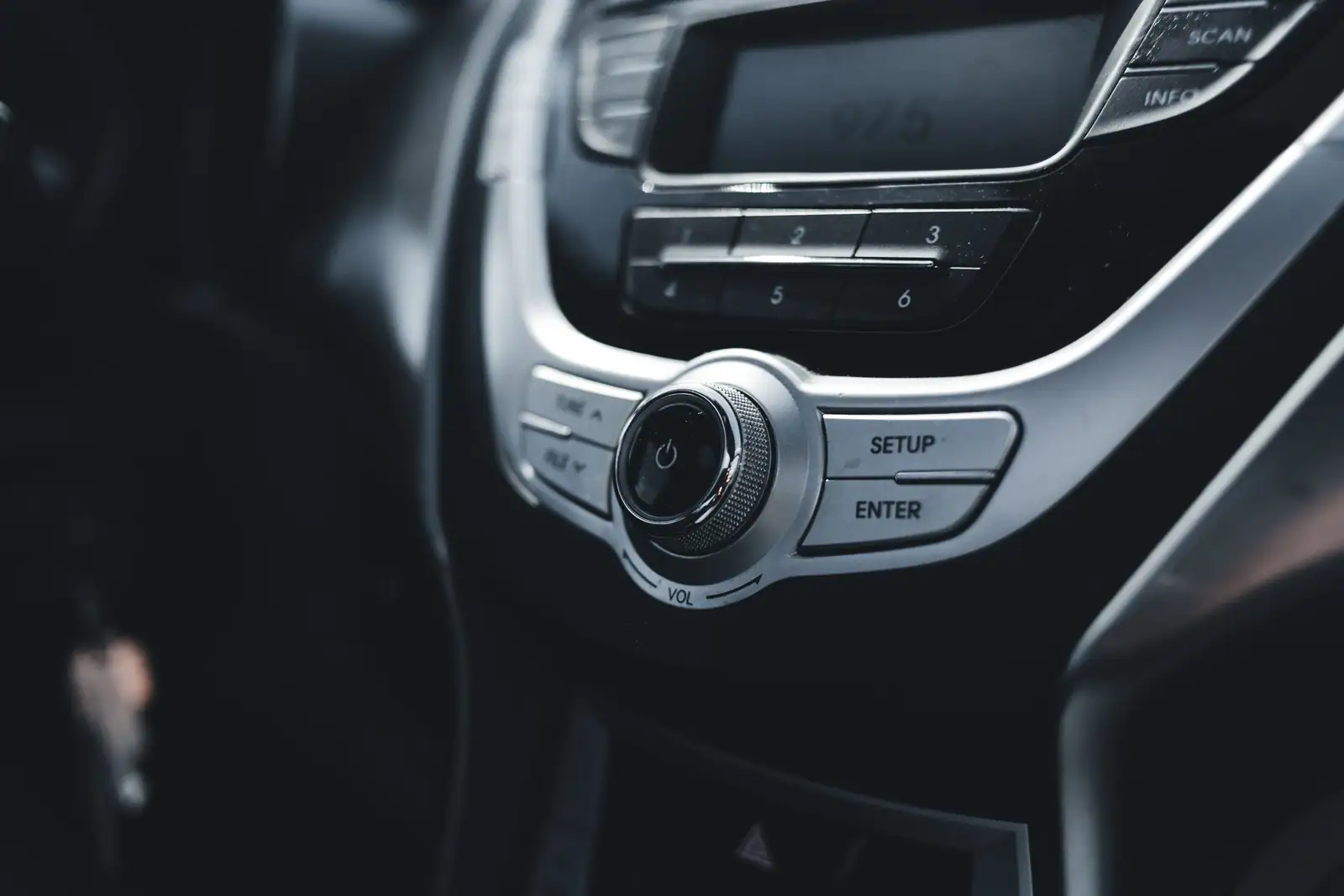 Autoradio en gros plan : molette de volume, présélections et afficheur indiquant une fréquence FM.