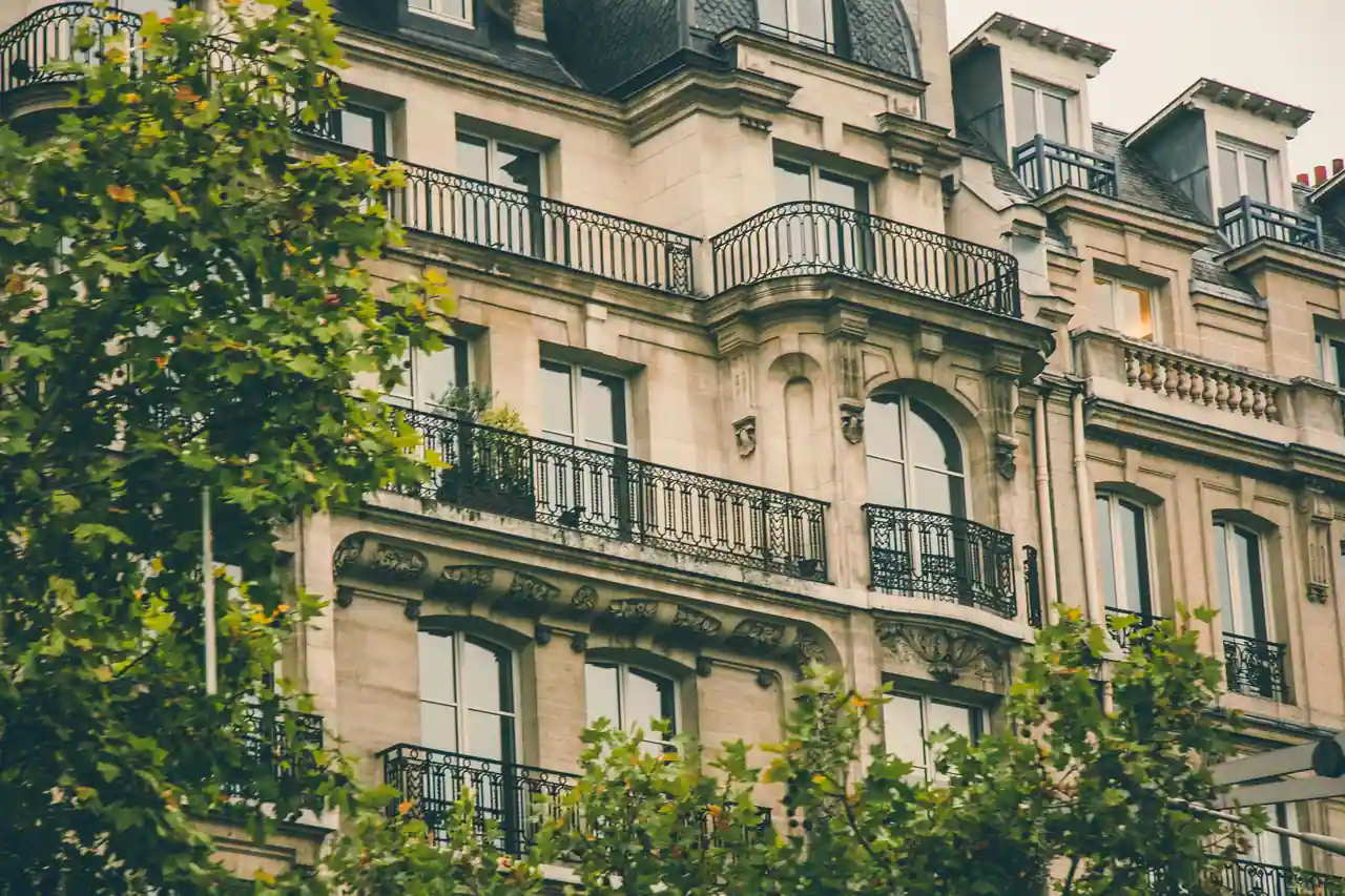 Façade parisienne en pierre de taille aux balcons de fer forgé, sous une toiture mansardée