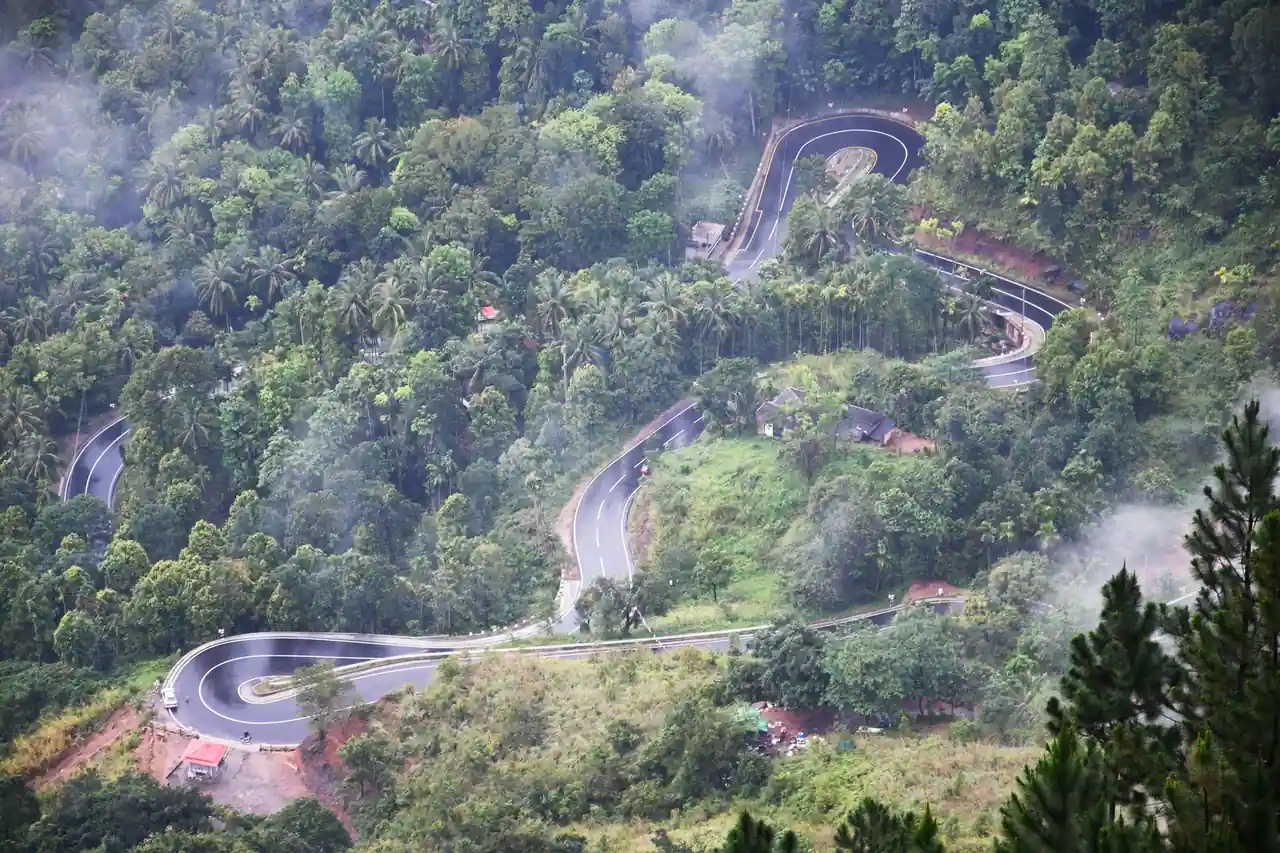 Route de montagne en lacets serrés traversant une forêt tropicale brumeuse au Sri Lanka.
